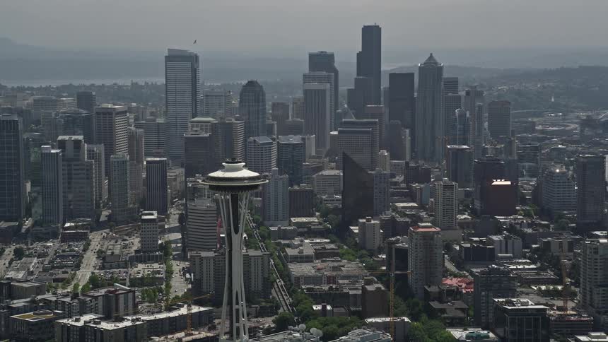 Aerial footage captures the iconic Space Needle standing tall above the skyscrapers and high rises of downtown Seattle revealing the citys stunning skyline on a partly cloudy day