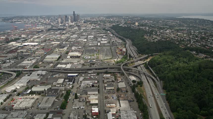 An aerial view from Interstate 5 tilting up to reveal downtown Seattle and industrial warehouses in Washington