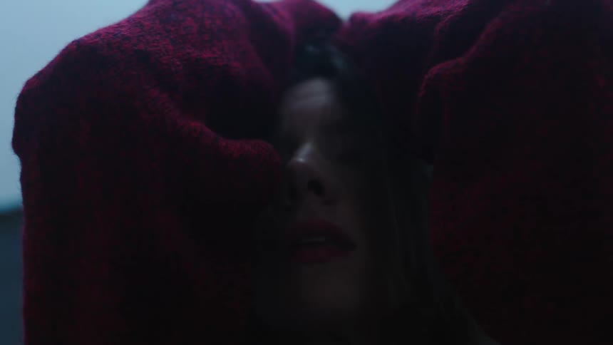 A young woman poses with her arms above her head