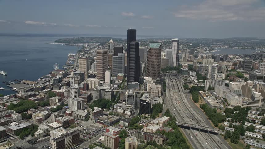 Aerial view of light traffic passing through Interstate 5 Express in Downtown Seattle tilting up to reveal towering skyscrapers