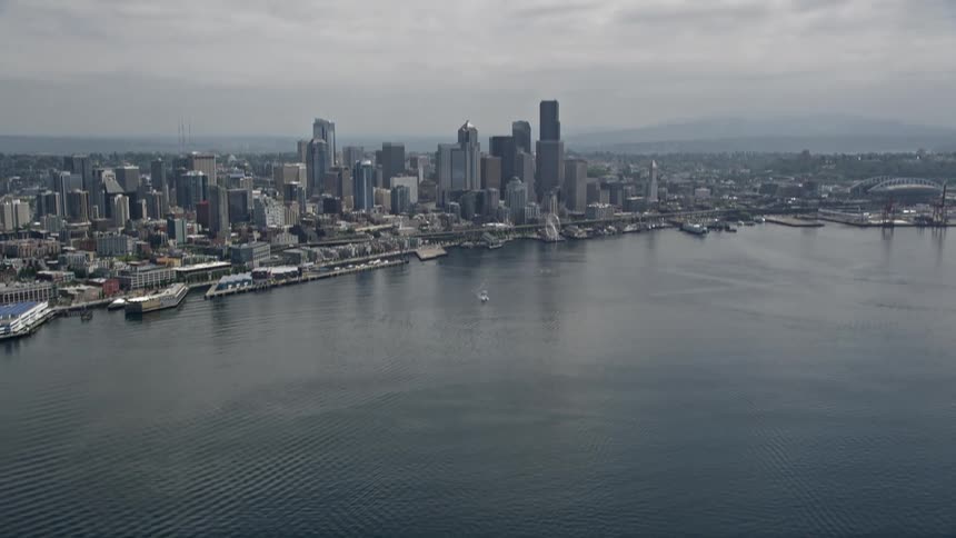An aerial shot of Seattles Downtown skyline taken from Elliott Bay with tall towers and skyscrapers standing out under cloudy skies