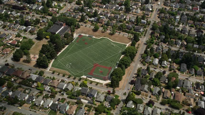 A sunny aerial view of a sports field in a suburban neighborhood showcasing baseball and soccer games in progress in the Ballard area of Seattle Washington