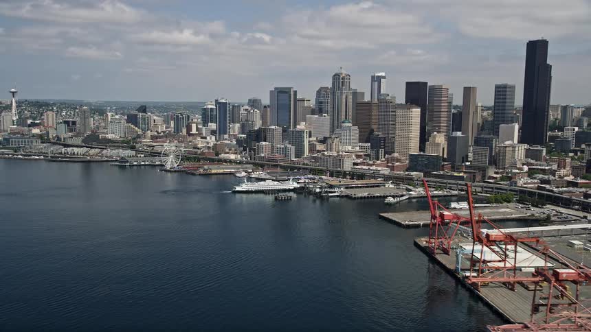 Approaching Downtown Seattles skyline and Waterfront piers from the port on a sunny day with aerial footage