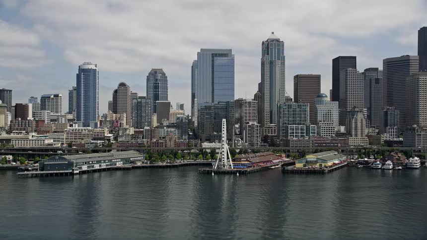 Flying over Downtown Seattle the Space Needle Seattle Ferry Terminal and the Great Wheel are revealed as the video captures the bustling metropolis and stunning coastline from above