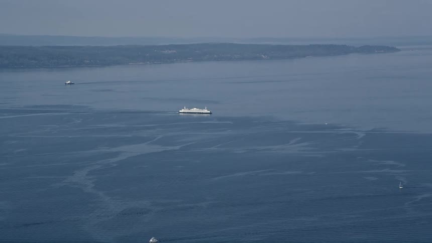 An aerial video captures a ferryboat sailing through the bright waters of Puget Sound in Washington state
