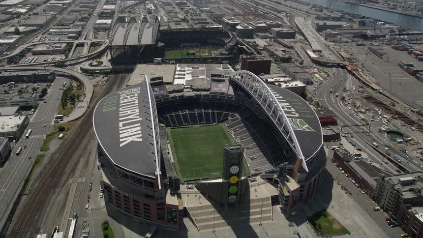A stunning 5K aerial view of CenturyLink Field in downtown Seattle during the day showcasing the football field inside the stadium with the city and waterfront in the background