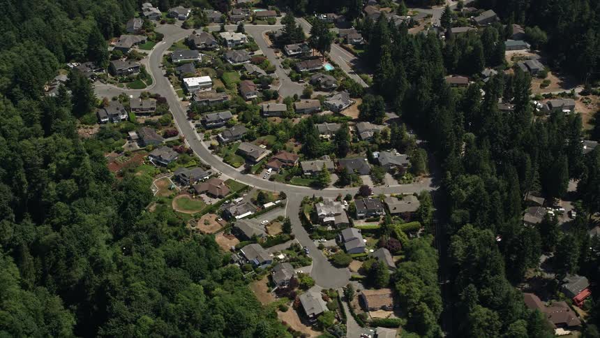 Flying over a sunny residential neighborhood in Lynnwood Washington surrounded by lush forest