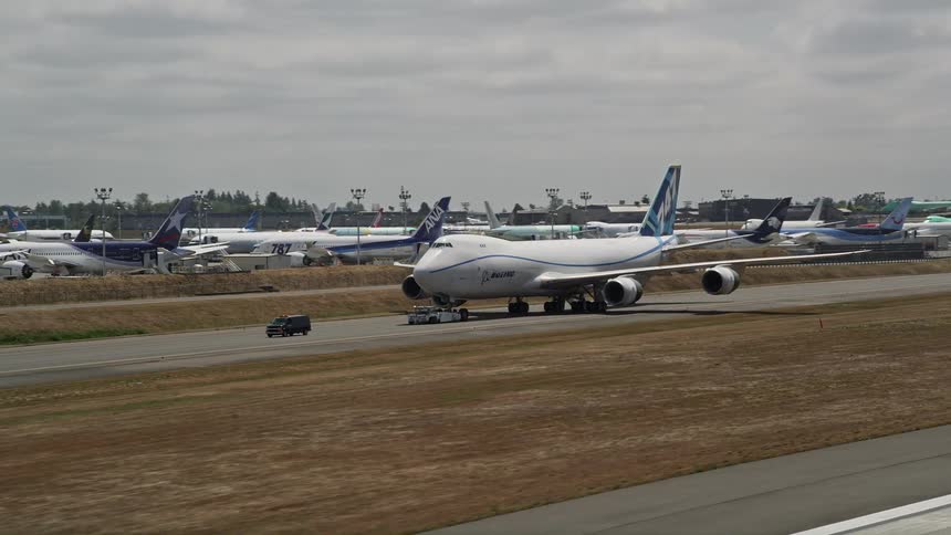 A 747 airplane taxis down the runway at Paine Field Washington under partly cloudy skies