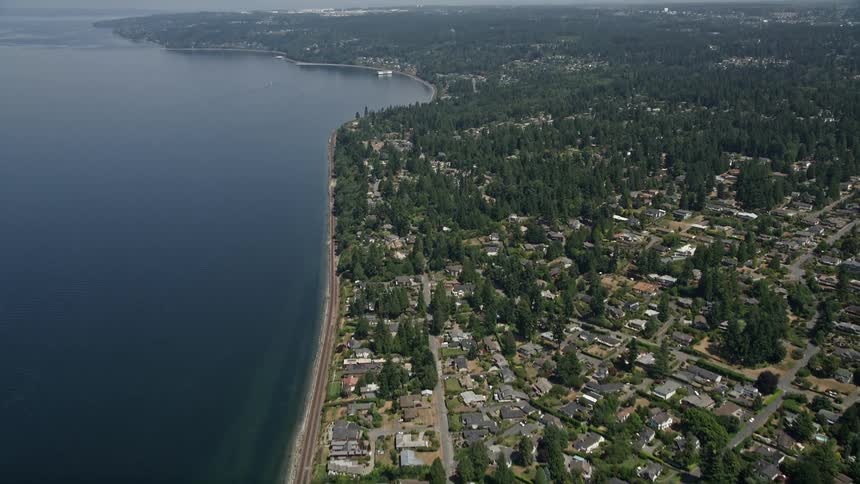 Aerial footage flying over railroad tracks and suburban homes along the waterfront of Edmonds and Lynnwood Washington