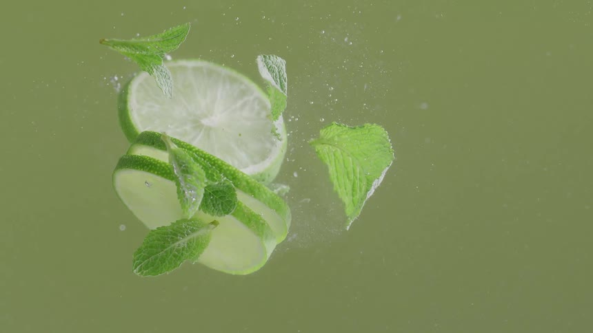 Lime slices and mint leaves float in bubbling liquid