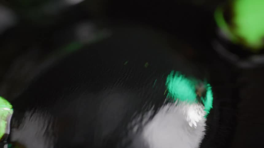 Large reflective bubble gyrates as it circles on liquid surface before it expands