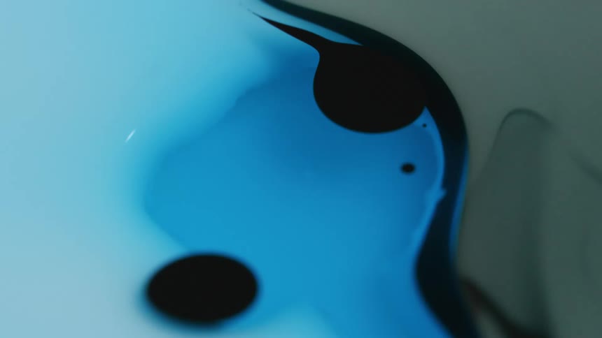 Black droplet falls on blue liquid