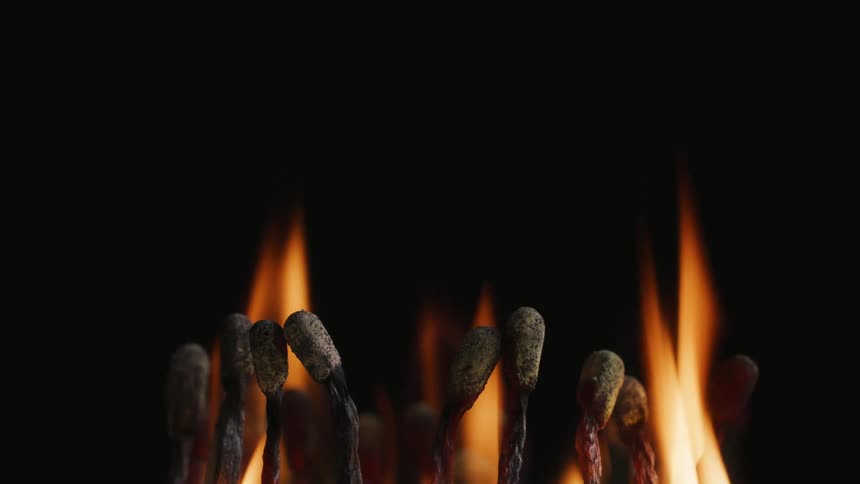 Clustered matches char as they burn against a dark background