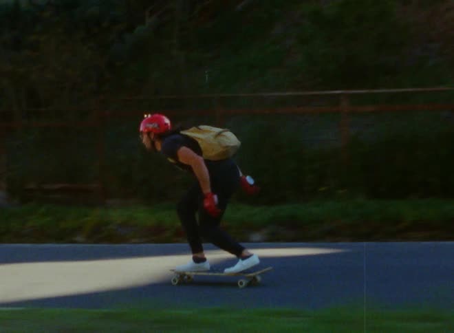A teenager skateboarding down a street bowing down to gain more speed