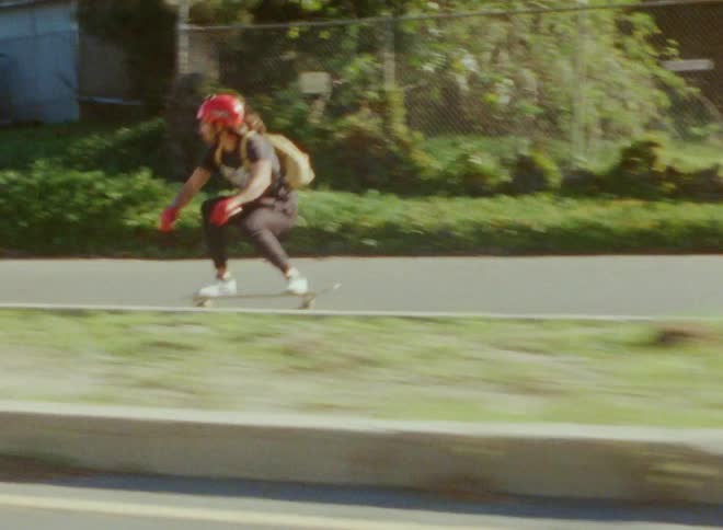 Skateboarder riding down road puts down hand to slow