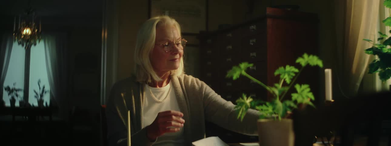An elderly woman looks at a framed picture and them smiles warmly