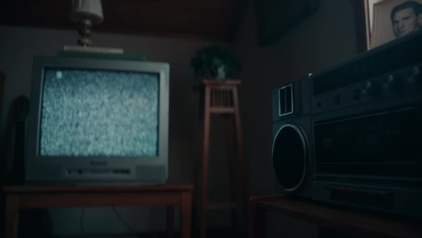 Static is on the screen of a portable television sitting on a table and a radio is on another table