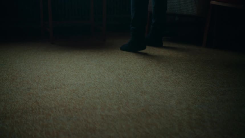 A carpeted floor as a person wearing black socks walks across the floor to a chair