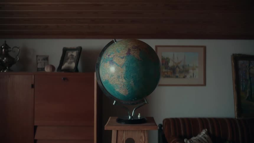 Close up of an earth globe resting over a small pedestal in the middle of a room