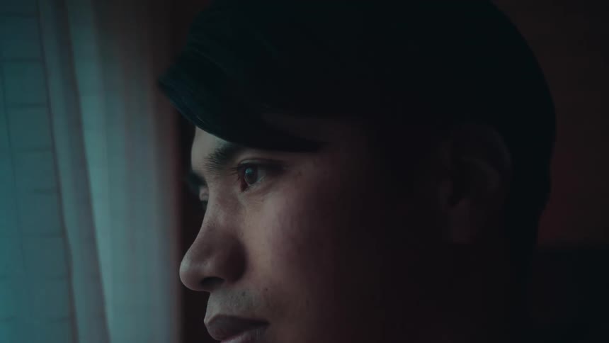A close up of a mans face as he looks out a window