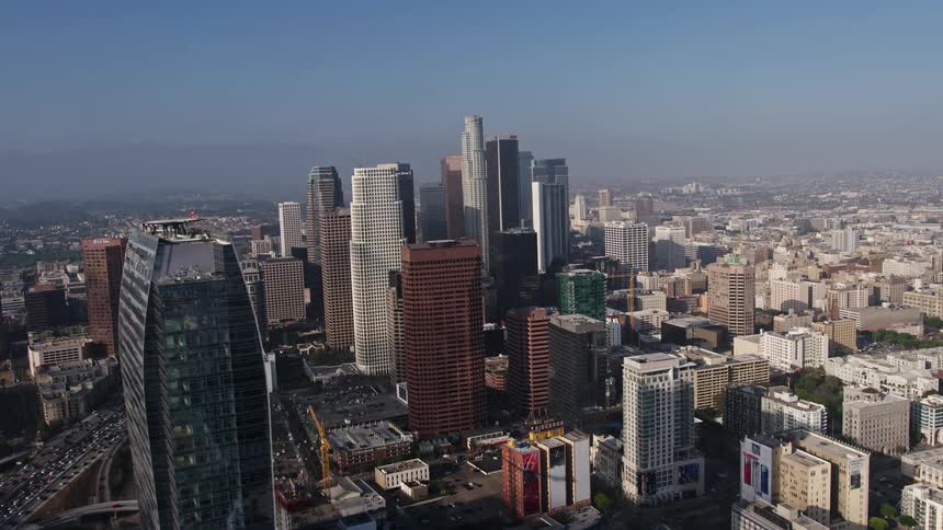 Aerial footage pans from heavy rush hour traffic to reveal Downtown Los Angeles skyscrapers Staples Center and the Ritz-Carlton hotel