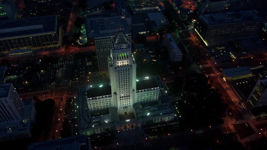 A stunning 4K aerial view of City Hall in Downtown Los Angeles during twilight shot in spring or summer from a birds-eye view and tilting down