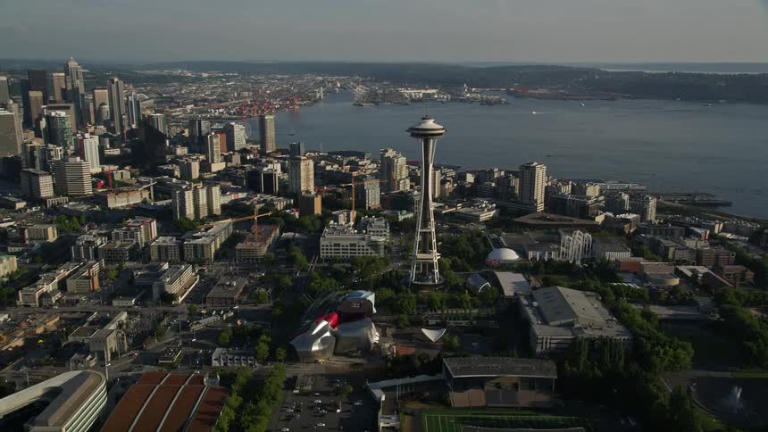 an aerial view of the Space Needle and downtown Seattle skyscrapers as the camera orbits around to reveal the bustling city below showcasing the beauty and magnificence of Washington's iconic landmarks