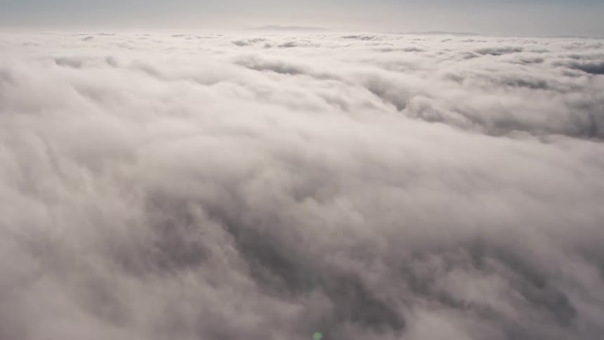 Flying above a dense sunlit marine layer over Los Angeles California in 4K aerial footage