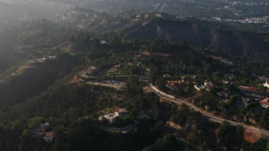 Aerial footage of hilltop mansions in Beverly Hills California on a hazy day