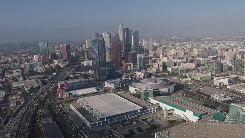 An aerial view of heavy rush hour traffic on the I-110 leading to the Staples Center and Ritz-Carlton in Downtown Los Angeles with towering skyscrapers in the background