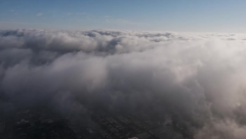 4K aerial footage showing a thick marine layer hovering over the urban landscape of Los Angeles during the day