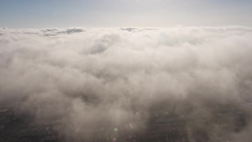 A breathtaking 4K aerial view of sunlit marine layer clouds blanketing urban landscape in Los Angeles California