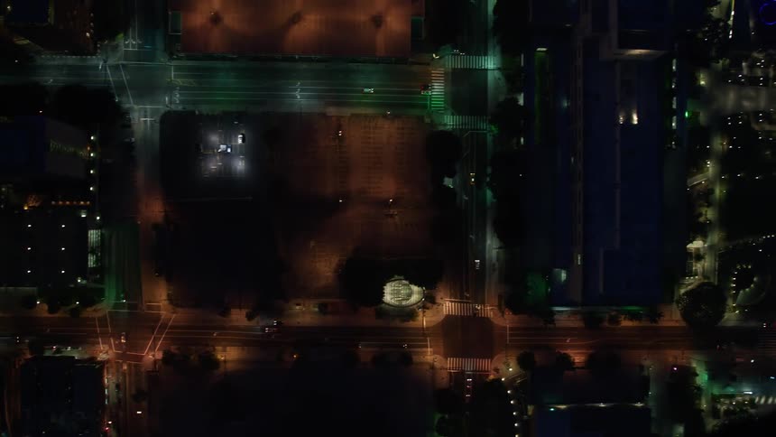 An aerial view at night of Downtown Los Angeles showcasing its streets and buildings illuminated by building and street lights