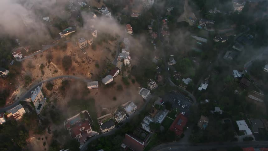 Aerial footage showcasing luxurious homes on the hills with a marine layer at sunset in Studio City California