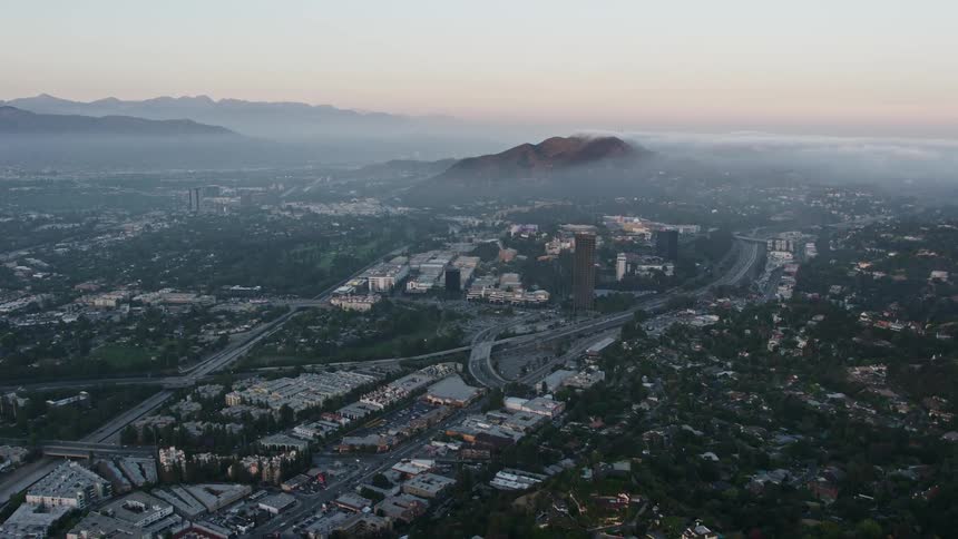 A stunning 4K aerial footage capturing the marine layer of fog approaching Universal City Universal Studios California during a mesmerizing sunset