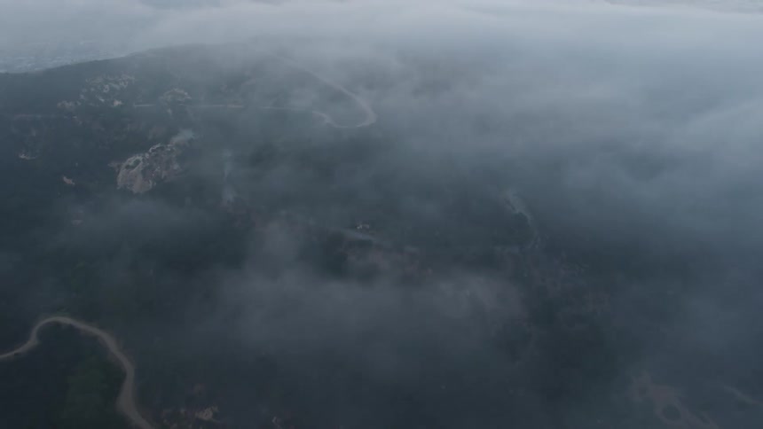 A stunning aerial view of winding roads through the foggy Hollywood Hills at sunset