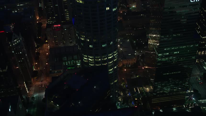 A stunning 4K aerial view of Los Angeles Public Library by night with a tilt down to the downtown area and its high rise buildings and skyscrapers