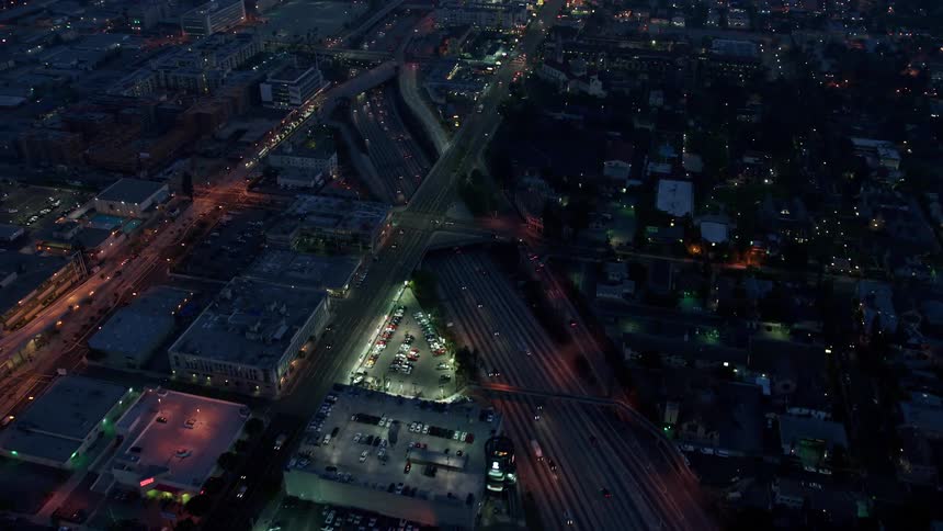 Aerial footage of light traffic on an LA interstate during twilight with a Southern California skyline in the background