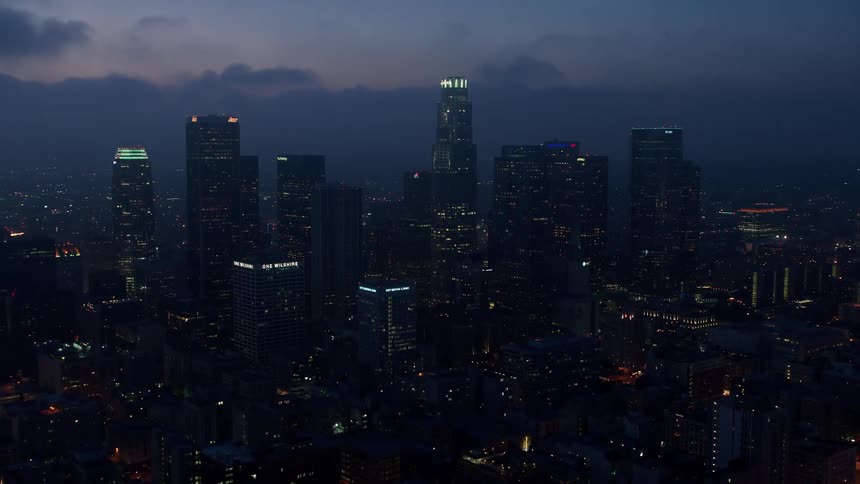 Flying over Downtown Los Angeles at twilight this 4K aerial footage captures the towering skyscrapers beneath the marine layer