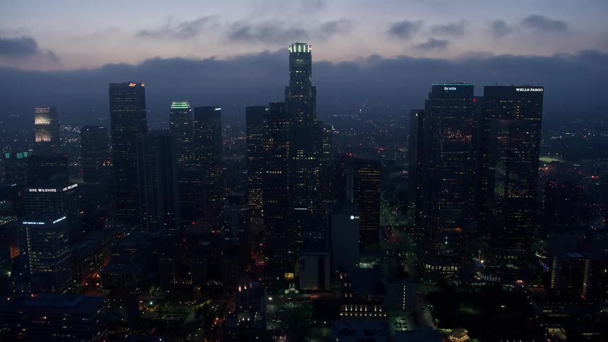 Approaching the Downtown Los Angeles skyline at twilight seen below a marine layer of fog in 4K aerial footage