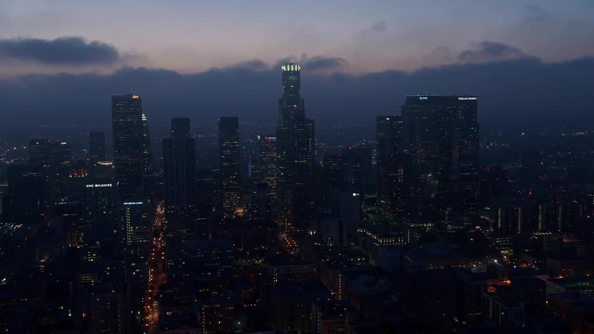 A stunning aerial view of Downtown Los Angeles skyscrapers below a marine layer during twilight