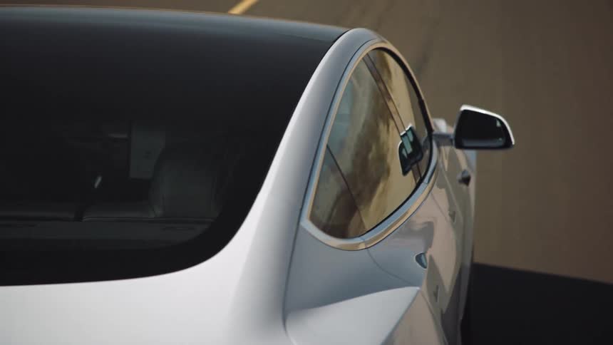 Car windows reflect surroundings as vehicle drives along highway