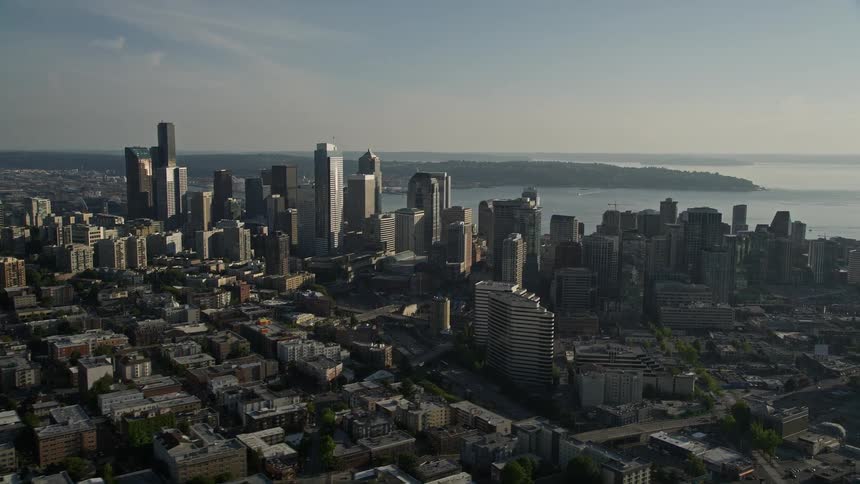 Aerial footage of the breathtaking downtown Seattle skyline showcasing the towering skyscrapers and high-rises set against the backdrop of the sparkling sea