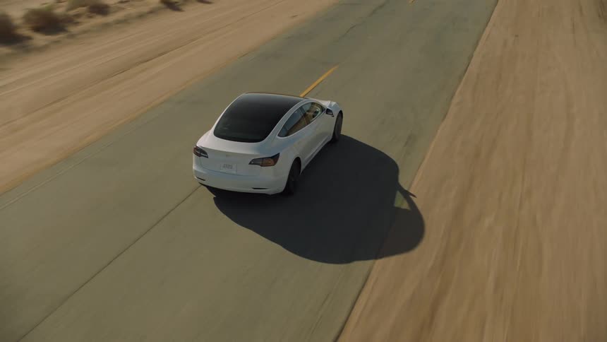 Pale car drives along two lane highway through countryside