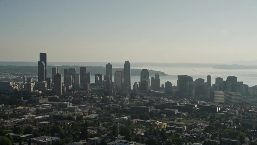 Approaching Downtown Seattle Washington from the east this aerial footage showcases the city's high rise buildings and vibrant cityscape on a sunny day