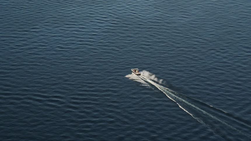 A small speedboat leaves a splashing trail as it tracks across Lake Washington offering a day-time recreational activity with beautiful aerial views of Seattle