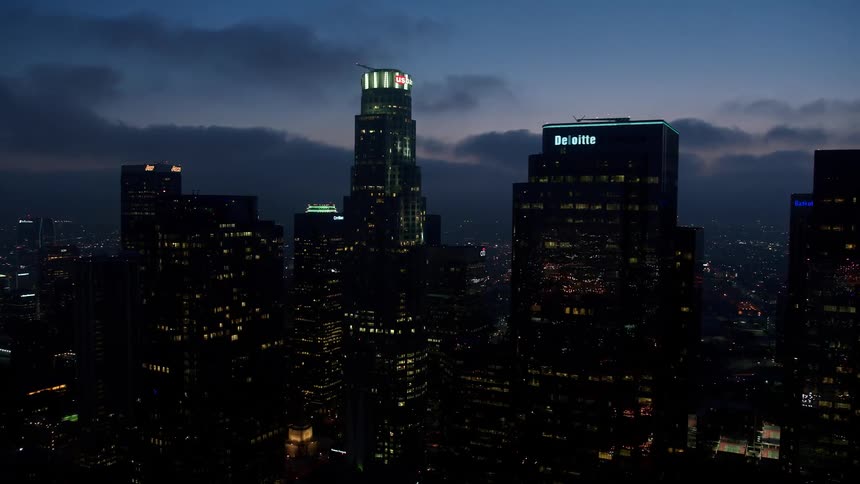 Flying over Downtown Los Angeles at twilight this clip showcases the towering US Bank Tower and other high rise buildings lighting up the bustling city below