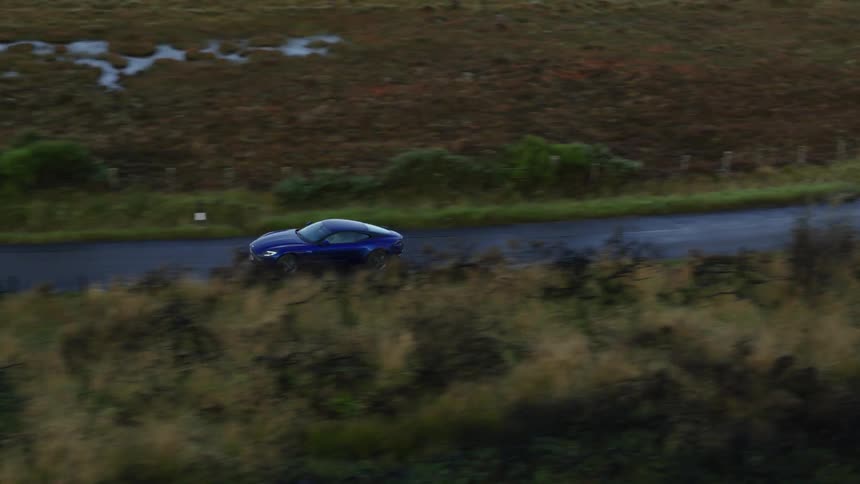 A car driving down a road crossing a grassy field