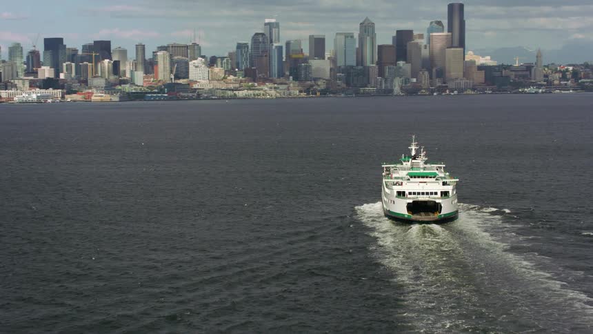 Aerial view of ferryboat sailing across water towards city skyline