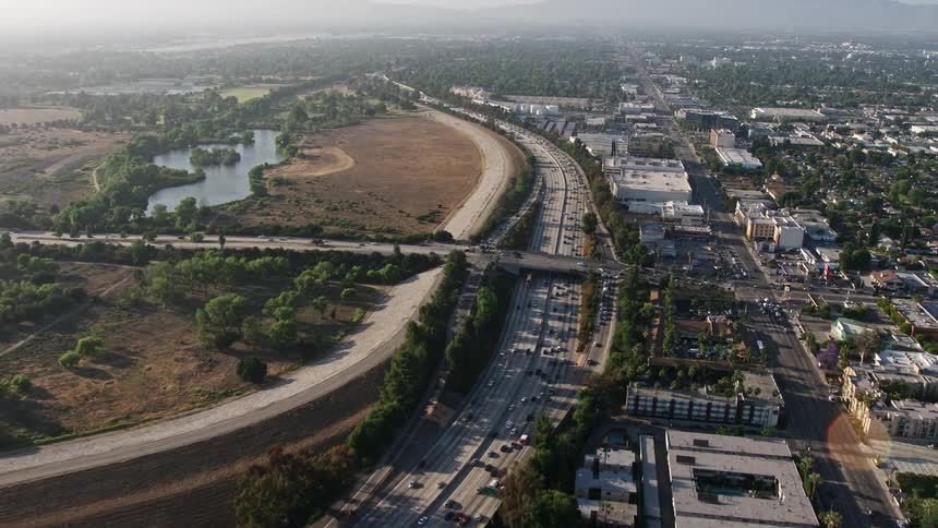 4K aerial footage showcasing heavy traffic on the I-405 freeway approaching Burbank Boulevard overpass near Woodley Park Van Nuys CA during a hazy daytime